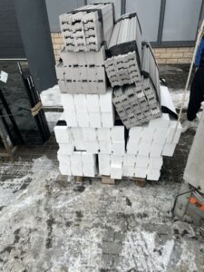 Szare listwy termiczne z XPS 700 Strong oraz białe bloki podwalinowe z Polarytu pod okna HST ułożone na palecie.