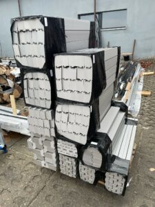 Palety z szarymi profilami termicznymi z XPS 700 Strong, wyciętymi na specjalne zamówienie pod ciężkie konstrukcje aluminiowe.